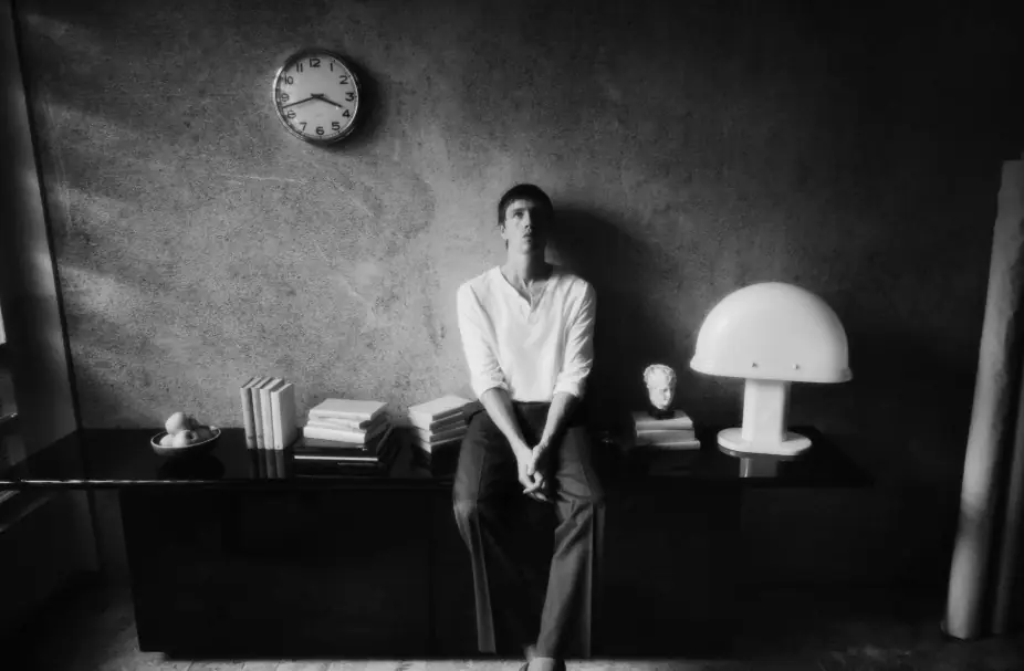 Photograph a person sitting in a room with a wall having a clock